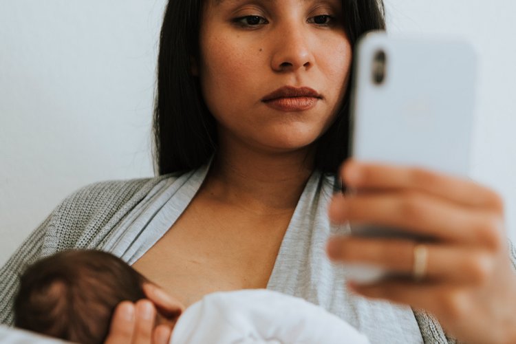 Stillende Mutter mit Smartphone